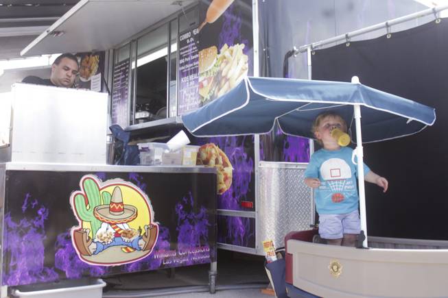 Wyatt, right, drinks his bottle from his umbrellaed wagon while posted up next to a food truck at the 2013 Clark County Fair, Saturday, April 13, 2013.