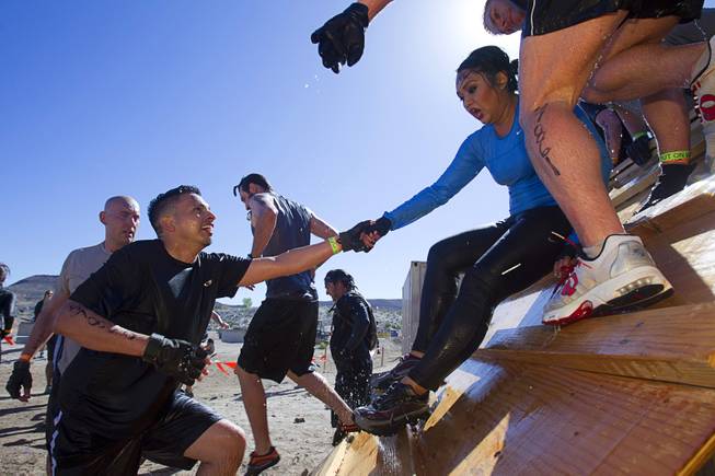 A man assists a companion during the Tough Mudder in Beatty, Nev. Sunday, April 14, 2013. Tough Mudder events are hardcore 10-12 mile obstacle courses designed to test all-around strength, stamina, mental grit, and camaraderie.