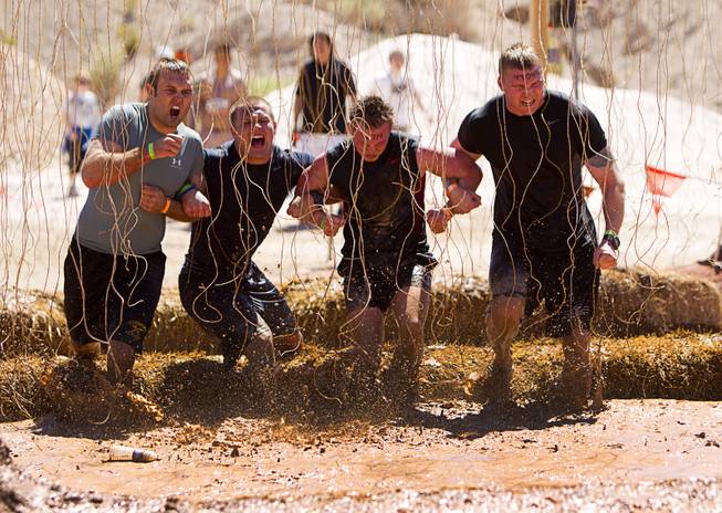 A group gets shocked by live wires in the "Electroshock Therapy" obstacle during the Tough Mudder in Beatty, Nev. Sunday, April 14, 2013. Tough Mudder events are hardcore 10-12 mile obstacle courses designed to test all-around strength, stamina, mental grit, and camaraderie.