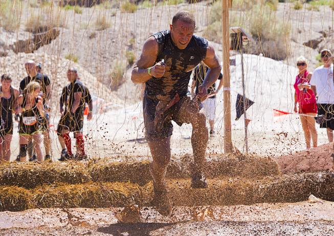A man runs through live wires in the "Electroshock Therapy" obstacle during the Tough Mudder in Beatty, Nev. Sunday, April 14, 2013. Tough Mudder events are hardcore 10-12 mile obstacle courses designed to test all-around strength, stamina, mental grit, and camaraderie.