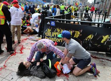 An injured woman is tended to at the finish line of the Boston Marathon,  in Boston, Monday, April 15, 2013. Two explosions shattered the euphoria of the Boston Marathon finish line on Monday, sending authorities out on the course to carry off the injured while the stragglers were rerouted away from the smoking site of the blasts.