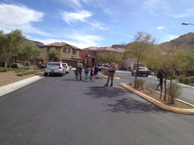 Children coming home from school are escorted by a police officer to their home near a crime scene where two children and a woman were found dead on Natures Glen Ave., and Jade River Lane on Friday, April 19, 2013.
