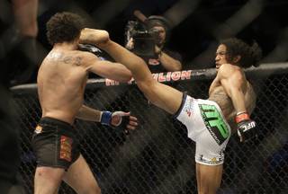 Benson Henderson, right, kicks Gilbert Melendez during the second round of a UFC lightweight championship mixed martial arts fight in San Jose, Calif., Saturday, April 20, 2013. Henderson won by split decision to retain the championship. (AP Photo/Jeff Chiu)