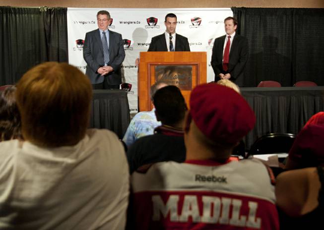 A fan wearing a Mike Madill jersey sits in the audience as Madill (center) fields questions with Wranglers team owner Gary Jacobs, left, and general manager Billy Johnson during a press conference announcing Madill being appointed head coach in April 2013.