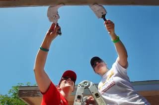 Laura Hoffmann, left, and Shawn Simon paint trim on a house as part of National Rebuilding Day Saturday, April 27, 2013.