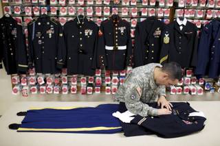 Staff Sgt. Miguel Deynes prepares the dress uniform of Capt. Aaron Blanchard, an Army pilot who was killed in Afghanistan, at the Dover Air Force Base in Deleware, April 27, 2013. At the Dover Port Mortuary, where the bodies of service members are brought to be prepared for funeral, no detail is too small, whether the coffin is closed or the body slated for cremation. (Ashley Gilbertson/The New York Times)