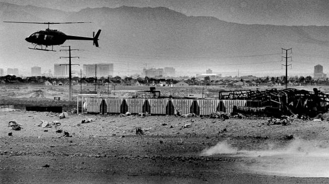 A helicopter flies over the smoldering remains of the Pacific Engineering Production Company of Nevada after two large explosions destroyed the plant, May 7, 1988.  