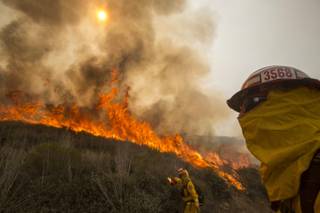 A firefighter watches a wildfire along a hillside in Point Mugu , Calif. Friday, May 3, 2013. Firefighters got a break as gusty winds turned into breezes, but temperatures remained high and humidity levels are expected to soar as cool air moved in from the ocean and the Santa Ana winds retreated.
