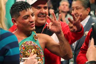 Abner Mares holds up three fingers signifying championships in three different weight classes after defeating featherweight champion Daniel 