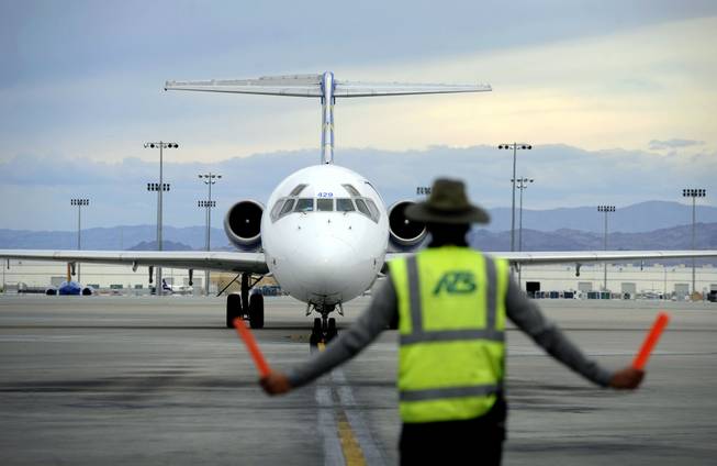 In this Thursday, May 9, 2013, photo, an airline ground worker guides an incoming Allegiant Air jetliner at McCarran International Airport, in Las Vegas. While other U.S. airlines have struggled with the ups and downs of the economy and oil prices, tiny Allegiant Air has been profitable for 10 straight years.