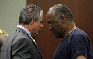 O. J. Simpson (R) talks with his attorney Ozzie Fumo after arriving for the second day of an evidentiary hearing in Clark County District Court on May 14, 2013 in Las Vegas, Nevada. Simpson, who is currently serving a nine-to-33-year sentence in state prison as a result of his October 2008 conviction for armed robbery and kidnapping charges, is using a writ of habeas corpus to seek a new trial, claiming he had such bad representation that his conviction should be reversed. Steve Marcus/pool
