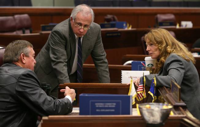 Nevada Assembly Republicans Cresent Hardy, left, and Pat Hickey, center, talk with Speaker Marilyn Kirkpatrick, D-Las Vegas, on the Assembly floor at the Legislative Building in Carson City, Nev., on Tuesday, Feb. 26, 2013. Earlier Tuesday Kirkpatrick introduced a measure that would streamline the Nevada First law that gives bidding preference on public works projects to contractors who hire Nevadans. (AP Photo/Cathleen Allison)