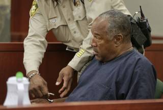 O.J. Simpson has one of his handcuffs removed as he takes the witness stand during an evidentiary hearing in Clark County District Court, Wednesday, May 15, 2013 in Las Vegas. 