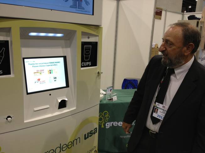 Company salesman Craig Gordon of Las Vegas discusses Greenredeem USA's kiosk that accepts cups, cans and bottles, and in return prints out coupons for retailers at RECon, the retail industry trade show at the Las Vegas Convention Center, on May 20, 2013.