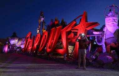 A tourist takes a photo at the Neon Museum in Las Vegas on Friday, May 24, 2013. For the past six months, visitors have had to squint up at the hulking metal forms through the desert sun. On Friday, the museum unveiled nighttime hours. 