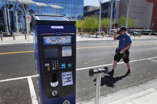 City of Las Vegas parking meter technician Matt Lancaster walks past one of the city's new electronic, solar powered parking meters while removing old meters Tuesday, June 4, 2013.