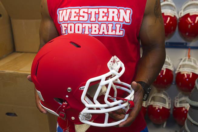 Western High School football coach Donnie Davis holds a new helmet at the school Monday, June 10, 2013. The high school football programs at Chaparral and Western received donations of $500,000 to upgrade everything from the weight room to field equipment and new uniforms.