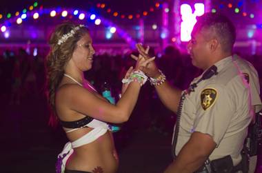 Sky Corona, 20 of La Habra, Calif. gives a bracelet to Metro Police Officer Pablo Torres during the third day of the Electric Daisy Carnival at the Las Vegas Motor Speedway early Monday morning, June 24, 2013.