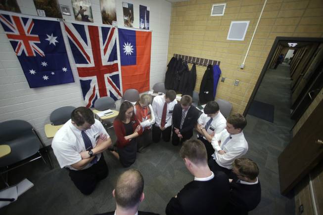 In this Jan. 8, 2013, file photo, Mormon missionaries pray before the start of a class in Mandarin Chinese language at the Missionary Training Center, in Provo, Utah.  Mormon missionaries will soon spend less time knocking on doors and more time chatting online with potential converts.