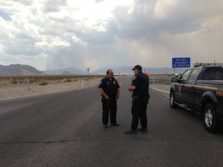 Smoke from a wildfire rises from Mount Charleston as Nevada Highway Patrol Troopers Roger Fickle, left, and Brian Drohn man a checkpoint along State Route 157 near U.S. 95.
