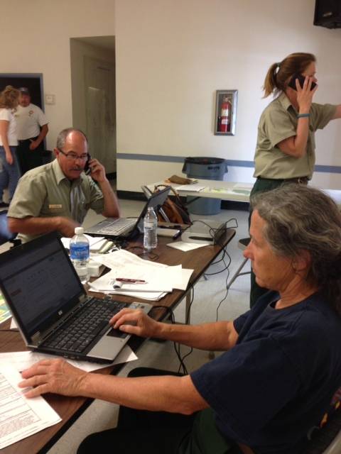 U.S. Forest Service spokeswoman Betsy Ballard (on laptop), Forest Service spokesman Jay Nichols (seated on phone) and Park Service Ranger Genny Wilson of Carson City (standing on phone) monitor progress of the Carpenter 1 fire on Mount Charleston on July 5, 2013.