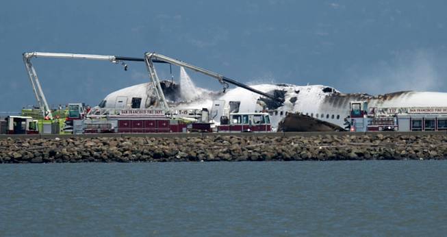 A firetruck sprays water on a Boeing 777 after Asiana Flight 214 crashed at San Francisco International Airport on Saturday, July 6, 2013, in San Francisco.
