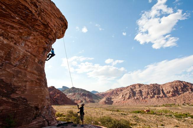 Simon Peck climbs the edge of a boulder as his friend, Dave Towse, belays the rope at Calico Basin west of Red Rock Canyon Conservation Area in Las Vegas Saturday, July 6, 2013.