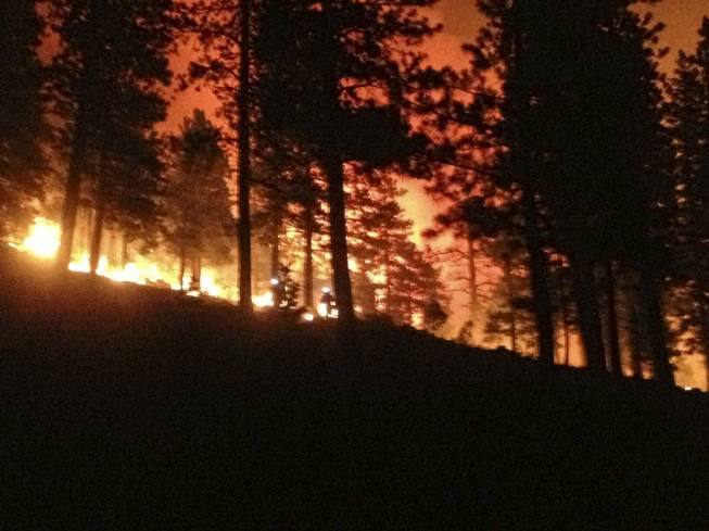 Two firefighters, center, with helmet lights on are seen working on the Mount Charleston fire during a night shift, Tuesday, July 9, 2013.