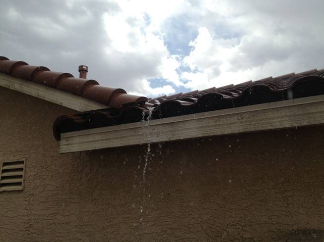 Rain runs off the roof of a Henderson home, Sunday, July 7, 2013. 
