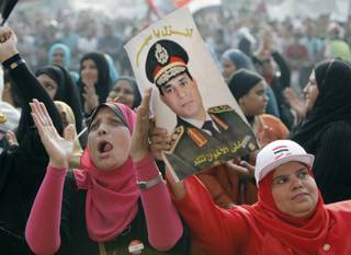 Egyptians chant slogans as they hold a poster of Egyptian Army Chief Lt. Gen. Abdel-Fattah el-Sissi during a protest in Tahrir Square in Cairo, Egypt, Monday, July 8, 2013. Egyptian soldiers and police opened fire on supporters of the ousted president early Monday in violence that left dozens of people killed, including one officer, outside a military building in Cairo where demonstrators had been holding a sit-in, government officials and witnesses said. Arabic reads: 