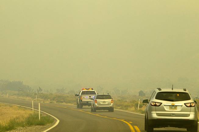 A Metro Police pickup truck leads a media convey through wildfire smoke on Kyle Canyon Road after a tour of fire activities on Mount Charleston Tuesday, July 9, 2013.