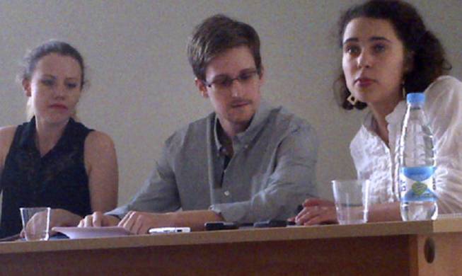 In this image provided by Human Rights Watch, NSA leaker Edward Snowden, center, attends a news conference at Moscow's Sheremetyevo Airport with Sarah Harrison of WikiLeaks, left, Friday, July 12, 2013. Snowden wants to seek asylum in Russia, according to a Parliament member who was among about a dozen activists and officials to meet with him Friday in the Moscow airport where he's been marooned for weeks. Duma member Vyacheslav Nikonov told reporters of Snowden's intentions after the meeting behind closed doors in the transit zone of Moscow's Sheremetyevo airport.