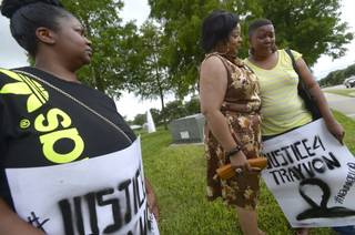 Lashauna Banks, left, of Gainesville, Fla., watches as her mother, Tara Banks, right, is consoled by Julie Yvette May, of Gordon, Ga. during a rally for Trayvon Martin outside the grounds of the Seminole County Courthouse in Sanford, Fla., Sunday, July 14, 2013. George Zimmerman was found not guilty in the 2012 shooting death of Martin.