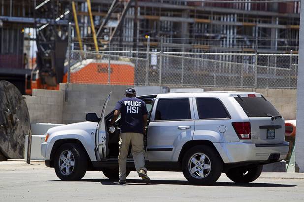 An investigator retrieves items from an SUV during a Homeland Security raid at a warehouse space behind the Power Exchange sex club on Highland Drive Wednesday, July 17, 2013.