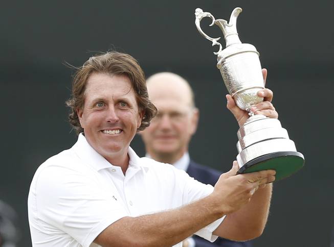 Phil Mickelson holds up the Claret Jug trophy after winning the British Open Golf Championship at Muirfield, Scotland, Sunday, July 21, 2013. 