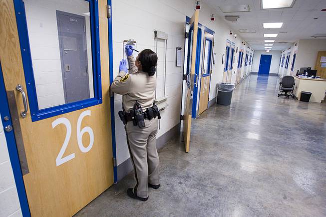 A corrections officer fills out out a log after visually checking on an inmate in a special housing area during a tour of the Clark County Detention Center Tuesday, July 23, 2013.