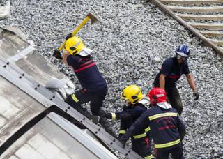 A firefighter uses and axe to open their way inside a train car at the site of a train accident in Santiago de Compostela, Spain, on Thursday, July 25, 2013. 