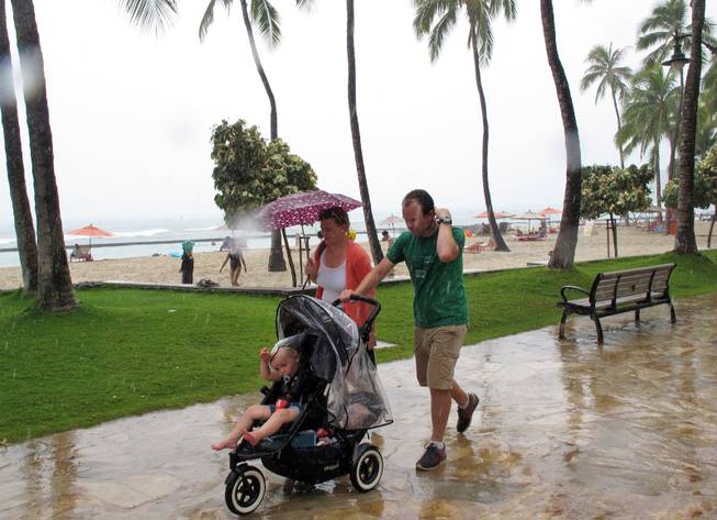Pedestrians walk along Waikiki beach in Honolulu on Monday, July 29, 2013, as Tropical Storm Flossie approached Hawaii. 