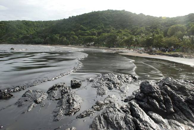 Streaks of crude oil cover the shore of Prao Bay on Samet Island in Rayong province eastern Thailand Monday, July 29, 2013. The oil spill that leaked from a pipeline has reached the popular tourist island in Thailand's eastern sea despite continuous attempts to clean it up over the weekend, officials said Monday. 