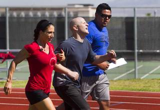 Metro Police recruit candidate Kristina Diamond, 33, and another candidate encourage Mike Donnelly, center, to complete his one mile run during  physical fitness testing at Cimarron-Memorial High School Thursday, Aug. 1, 2013.