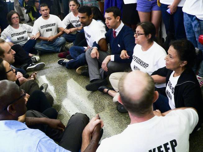 Theresa Navarro, right, and Bob Fulkerson, to her left, participate in a pro-immigration reform sit-in outside House Speaker John Boehner's office in the Longworth House Office Building in Washington, D.C., on Thursday, July 31, 2013.