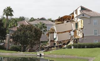 Damage to buildings caused by a sinkhole 40 to 50 feet in diameter is seen at the Summer Bay Resort, Monday, Aug. 12, 2013, in Clermont, Fla.  Lake County Fire Rescue Battalion Chief Tony Cuellar says about 30 percent of the three-story structure at Summer Bay Resort collapsed around 3 o'clock this morning. Another section was sinking.