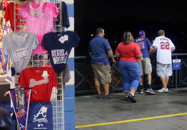 Baseball fans look over a railing at Turner Field near the scene where a man fell 30-40 feet from the upper deck Monday, Aug. 12, 2013. 
