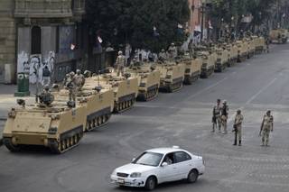Egyptian army soldiers take their positions on top and next to their armored vehicles while guarding an entrance to Tahrir Square, in Cairo, Friday, Aug. 16, 2013.