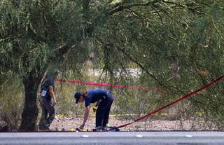 A crime scene analyst looks over a scene as Henderson Police investigate an officer-involved shooting near Boulder Highway and College Drive in Henderson, Aug. 20, 2013.  