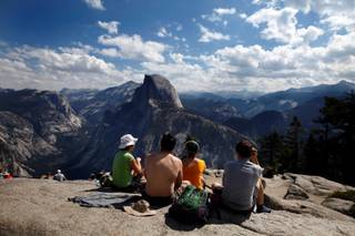 Tourists enjoy the view at Glacier Point in California's Yosemite National Park on August 27, 2013, as the Rim fire continues to rage about 25 miles away. As the devastating fire spreads deeper into Yosemite, would-be park visitors are having to decide whether to cancel plans made months or years in advance or press ahead with a visit that could potentially end in a smoky evacuation. Many are choosing to keep their date with El Capitan and Half Dome. 