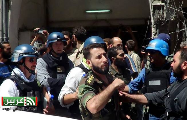In this citizen journalism image provided by the United media office of Arbeen which has been authenticated based on its contents and other AP reporting, UN investigation team with blue helmets, walk with Syrian rebels in Damascus countryside of Zamalka, Syria, Wednesday, Aug. 28, 2013. 