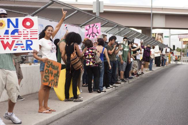 People hold up peace and anti-war signs during a protest against U.S. intervention in Syria held on Tropicana and the I-15, Saturday, Aug. 31, 2013.