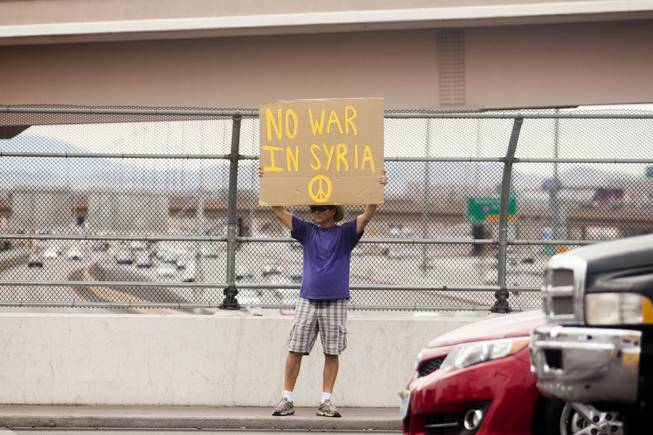 A man holds up a "No War In Syria" sign during a protest against U.S. intervention in Syria held on Tropicana and the I-15, Saturday, Aug. 31, 2013.