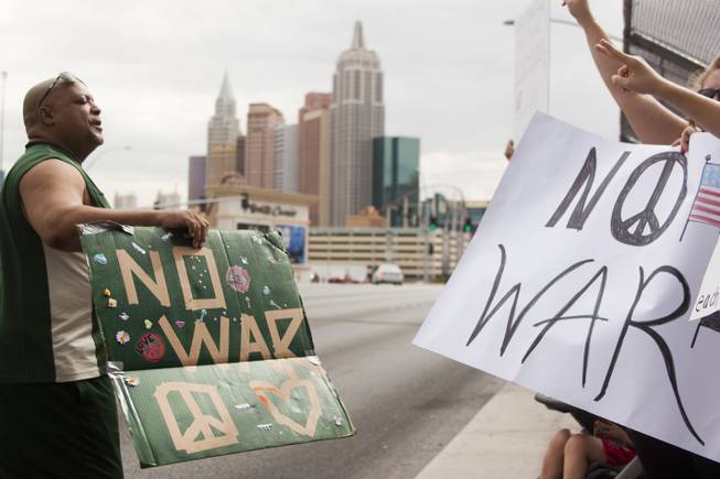 People hold up anti-war signs during a protest against U.S. intervention in Syria held on Tropicana and the I-15, Saturday, Aug. 31, 2013.
